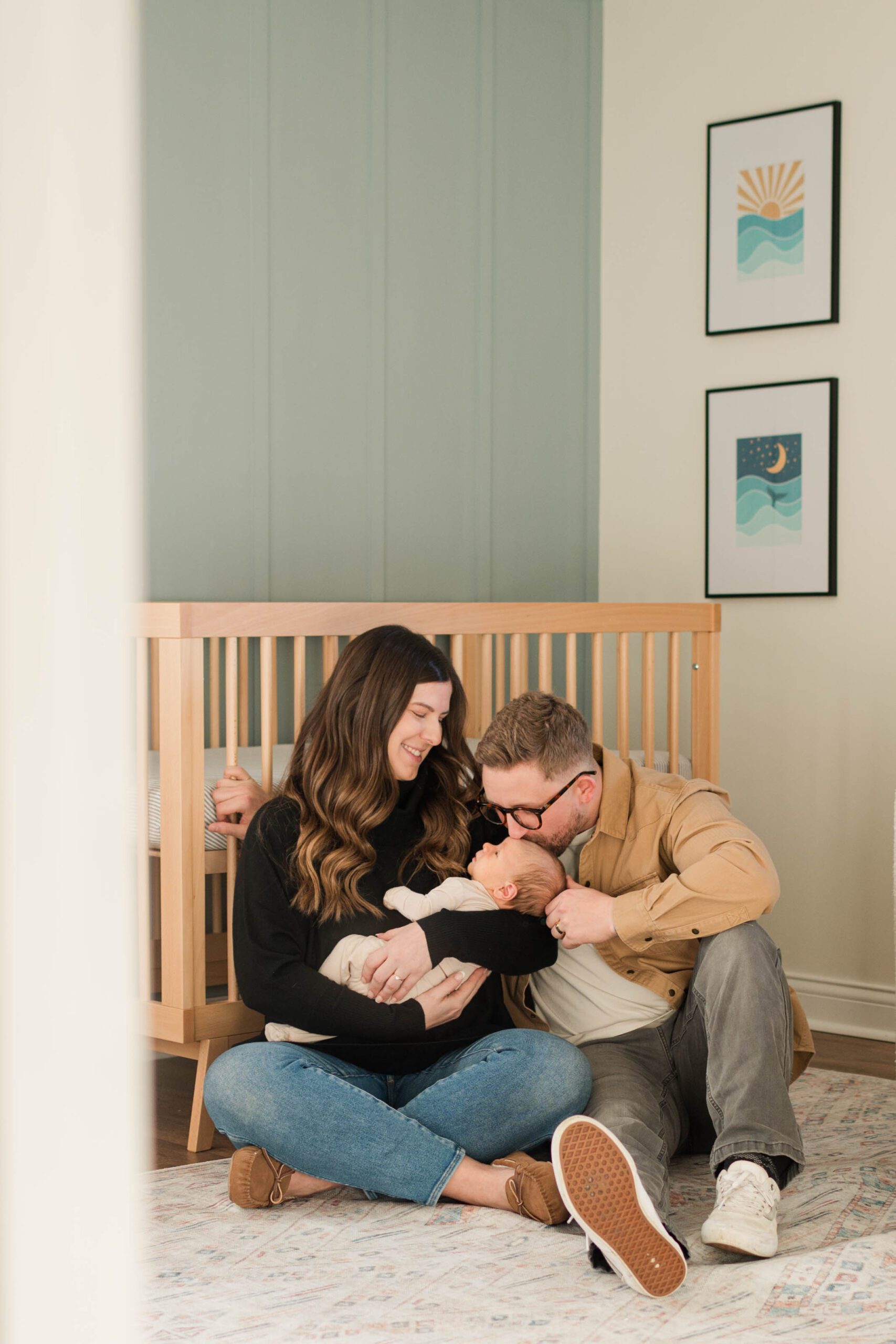 Family snuggles newborn baby in front of crib
