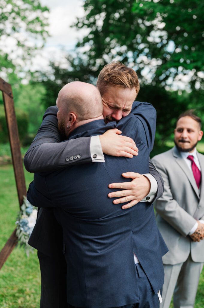 Groom and bride's father hug during ceremony. 
