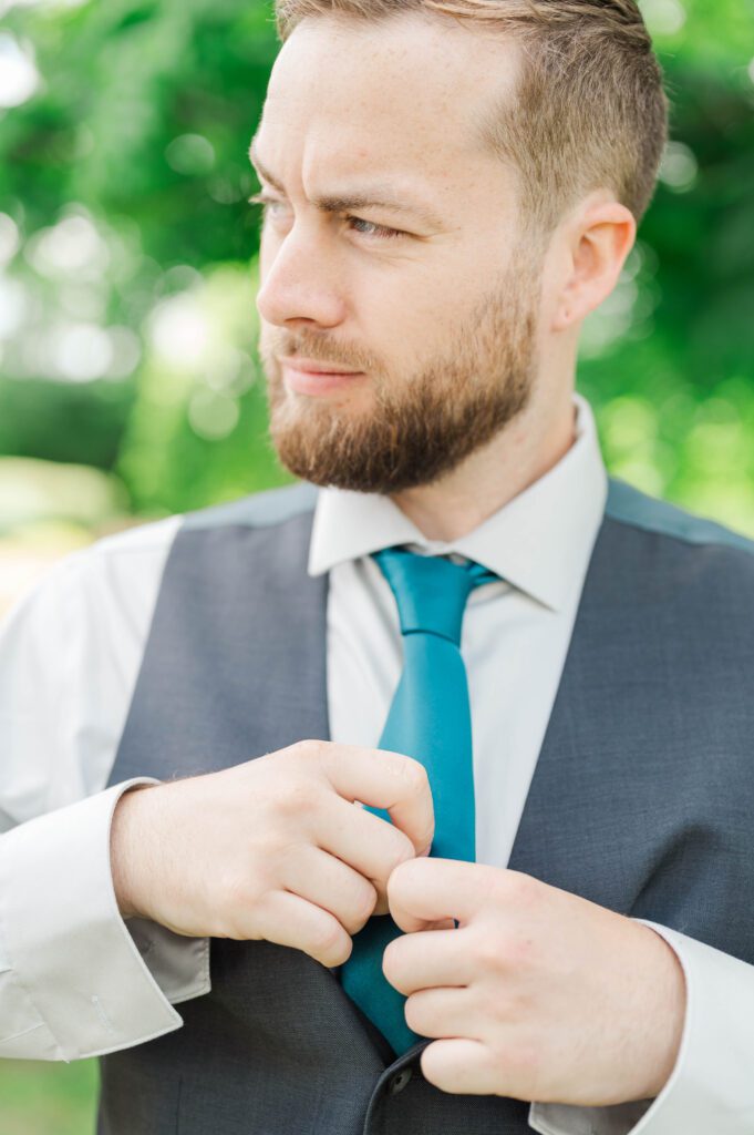 The groom straightening his tie on his Kentucky farm wedding day. 