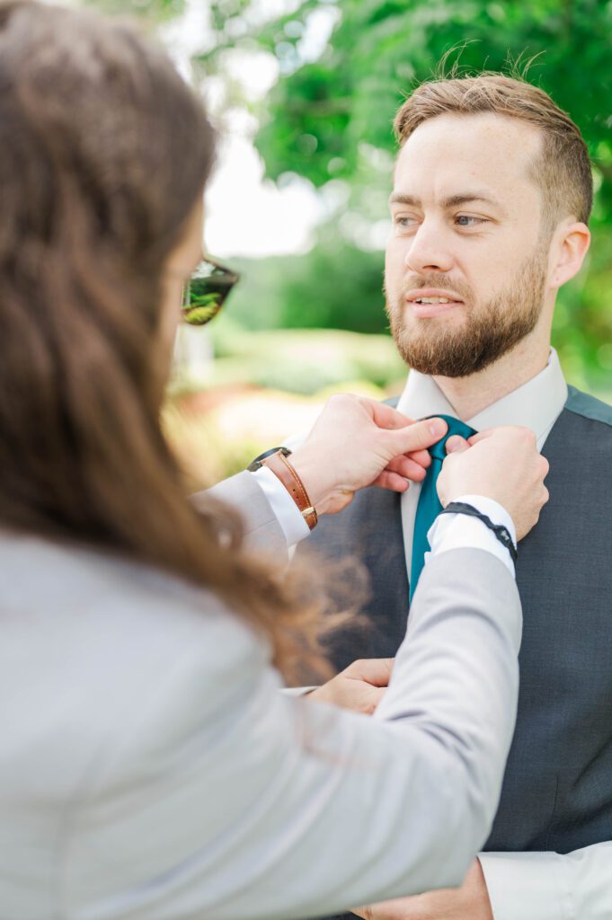 A groomsman helping the groom get ready on his wedding day.