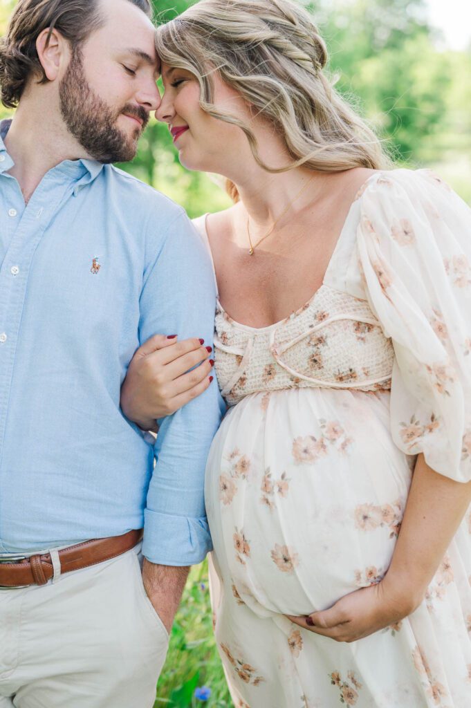 Couple stands together in wildflower field for their maternity photo session at Beckley Creek Park in Louisville