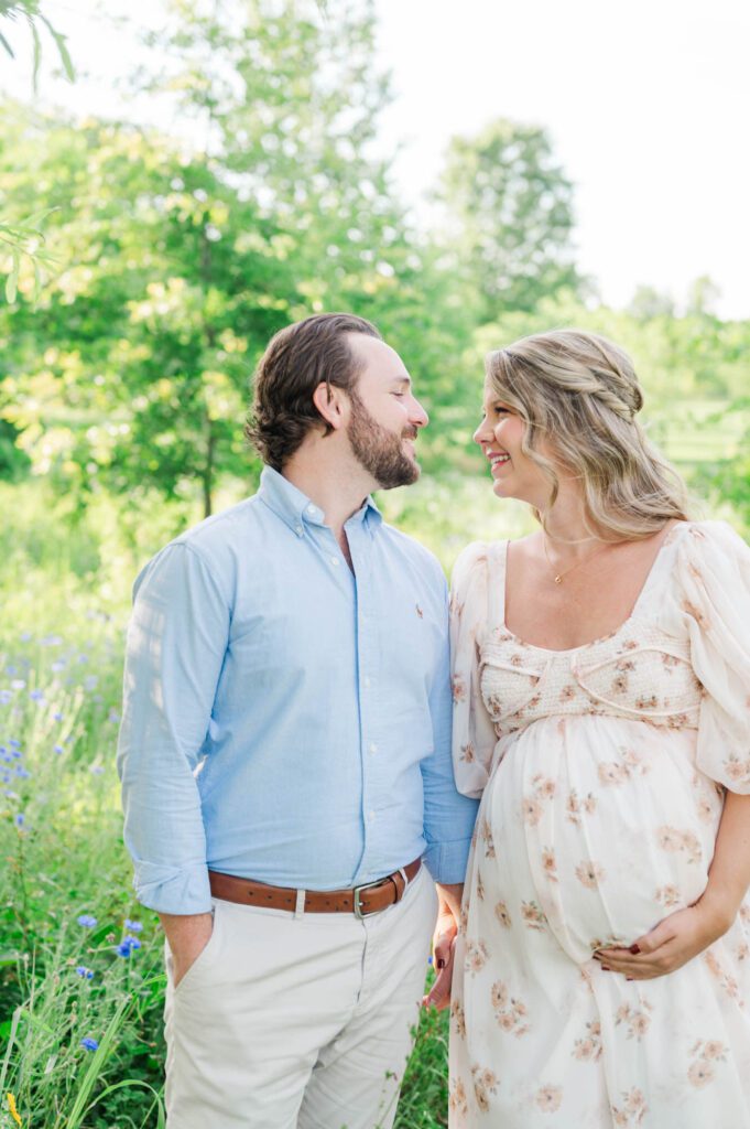Couple stands together in wildflower field for their maternity photo session at Beckley Creek Park in Louisville