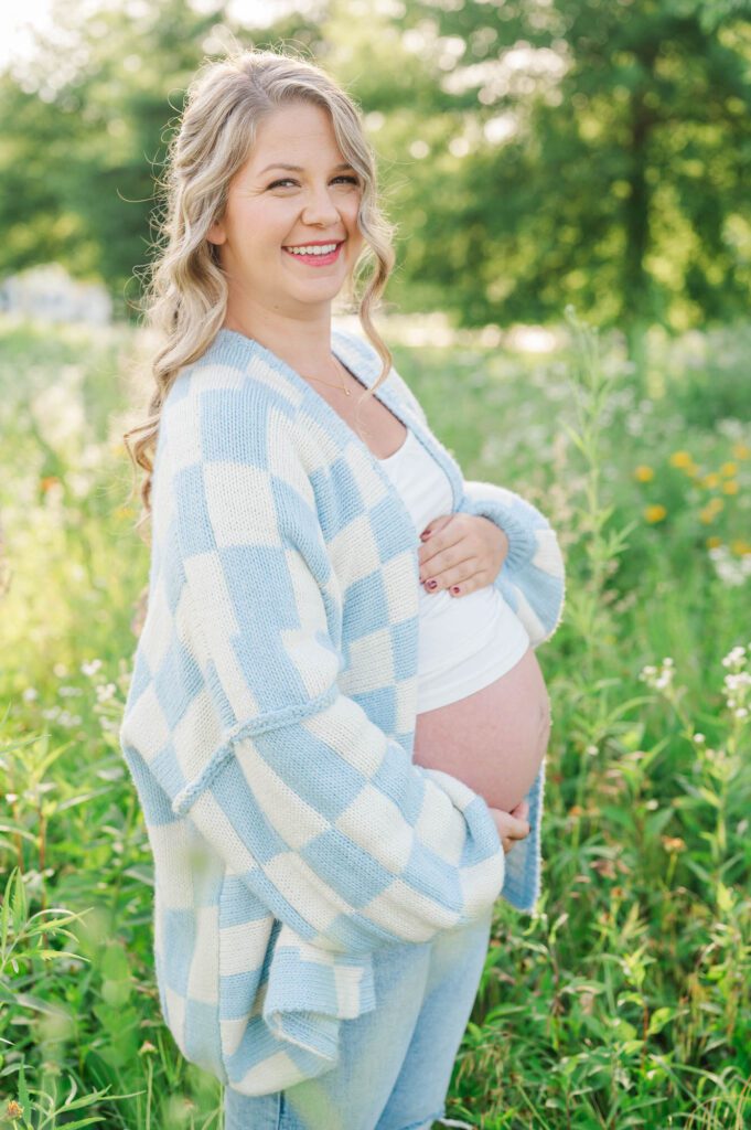 Expectant mother stands in wildflower field for maternity photo session at Beckley Creek Park in Louisville