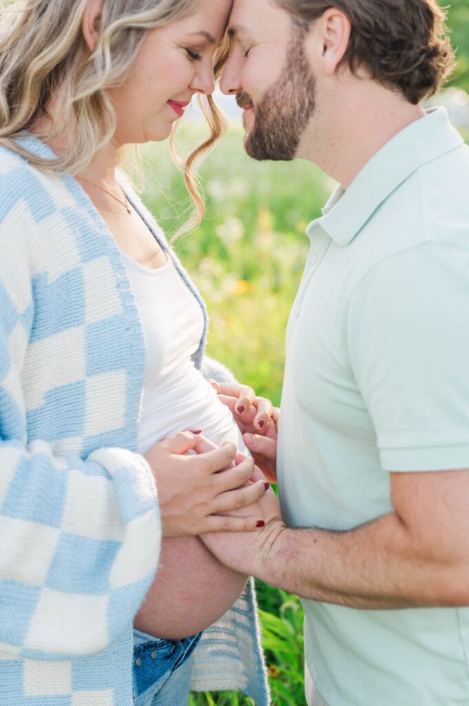 Couple stands together in wildflower field for their maternity photo session at Beckley Creek Park in Louisville