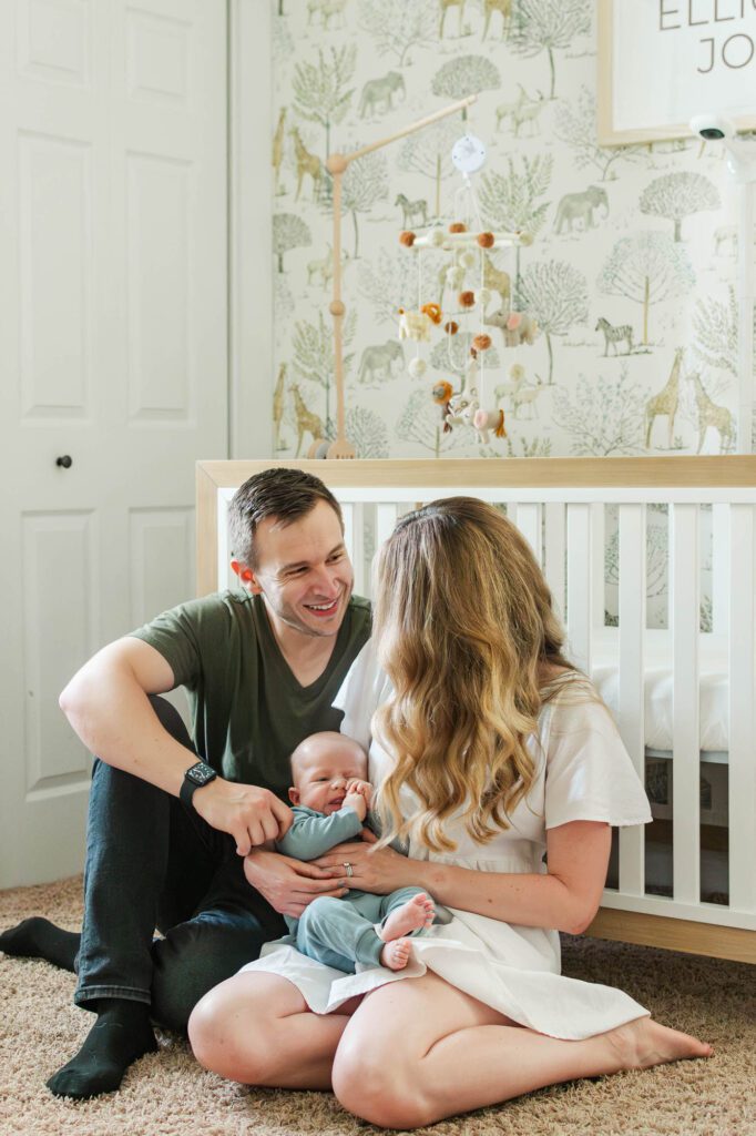 Family sits together in front of crib with their 3 month old for their Louisville in-home family session