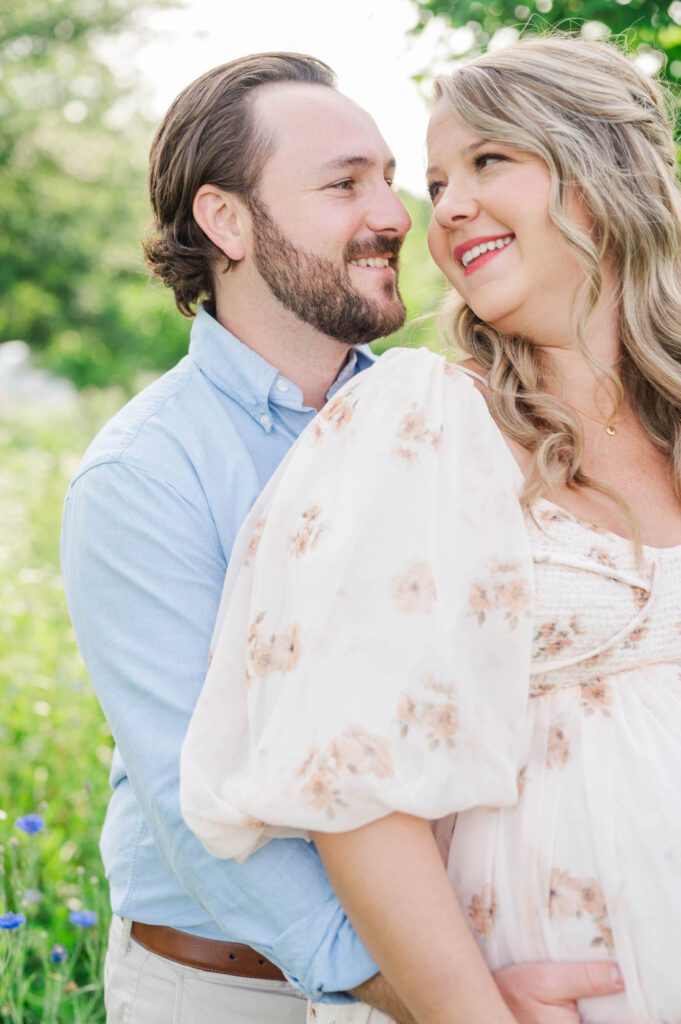 Couple stands together in wildflower field for their maternity photo session at Beckley Creek Park in Louisville