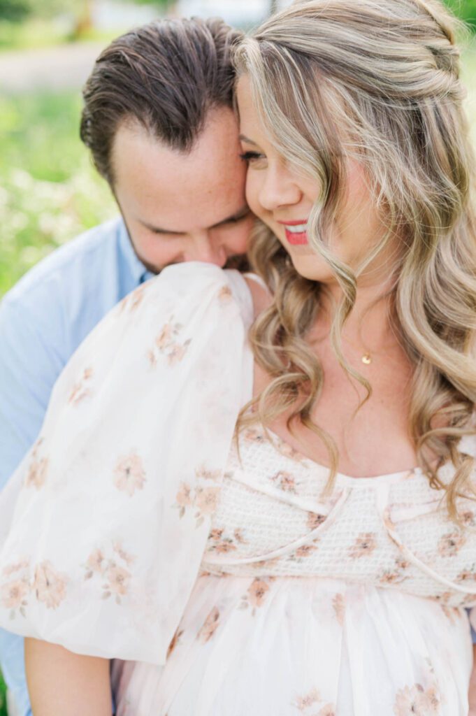 Couple stands together in wildflower field for their maternity photo session at Beckley Creek Park in Louisville