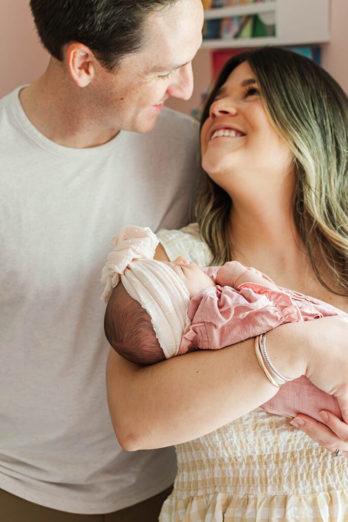 New mom and dad hold their baby girl in the nursery for their Louisville, KY in-home newborn session