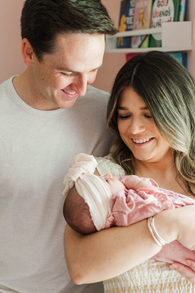 New mom and dad hold their baby girl in the nursery for their Louisville, KY in-home newborn session