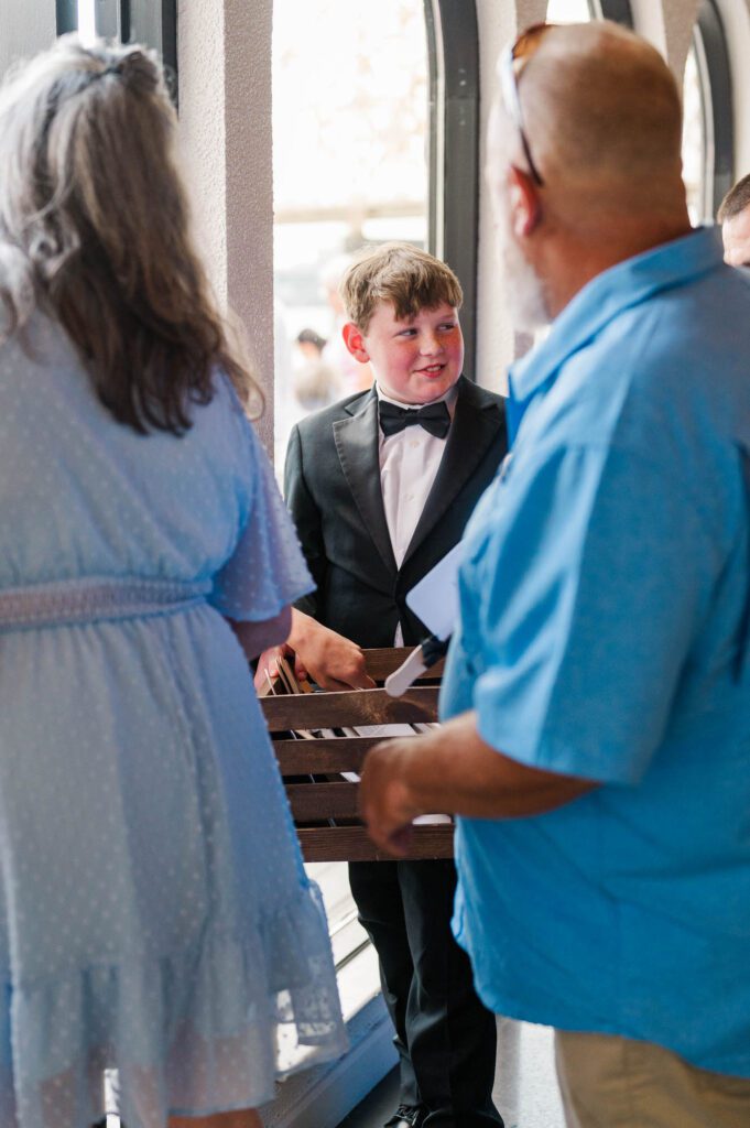 Young boy hands out fans to wedding guests on a wedding day at The Jefferson