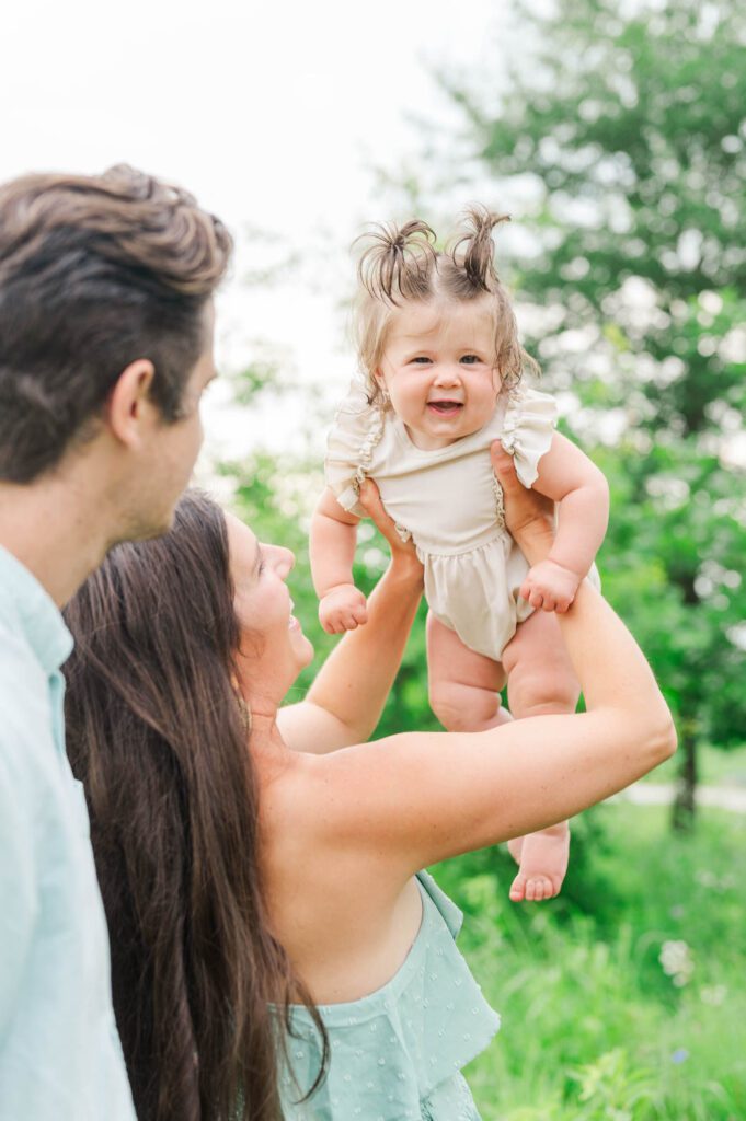 Mom holds baby girl up high as they play a game for their photo session in Beckley Creek Park in Louisville, KY
