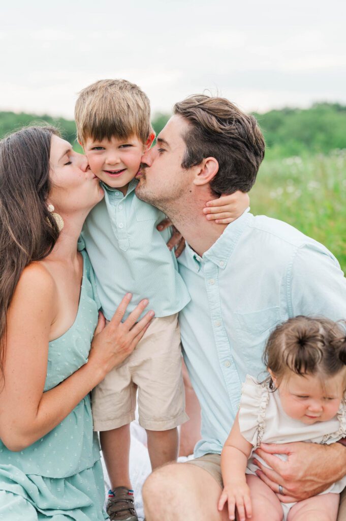 Mom and dad give son kisses on the cheek during their family photo session in Louisville