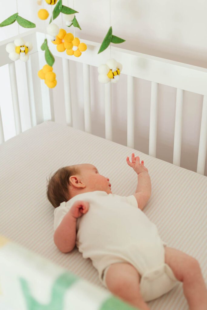 Baby girl lays in the crib in her nursery