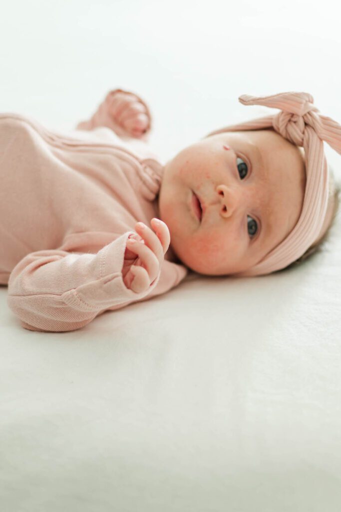 Baby girl laying on her parent's bed