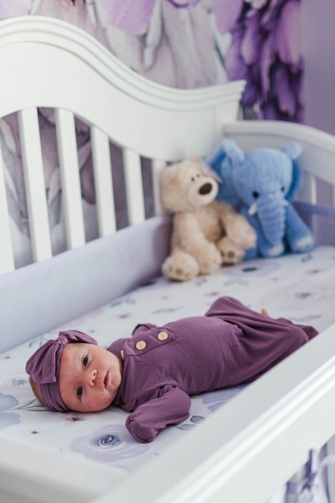 Newborn baby girl laying in the crib of her nursery
