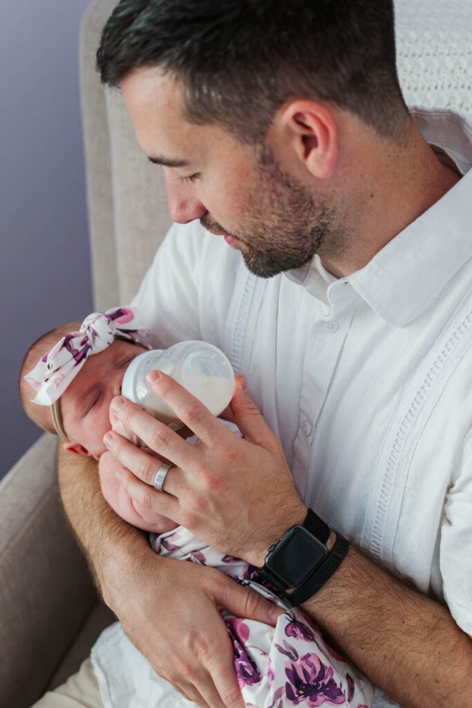 Dad smiles while holding baby girl during in-home newborn photography session in Lexington, KY