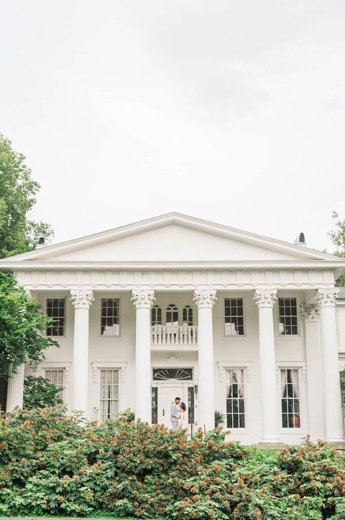 Couple stands in front of Whitehall in Louisville, KY on their wedding day.