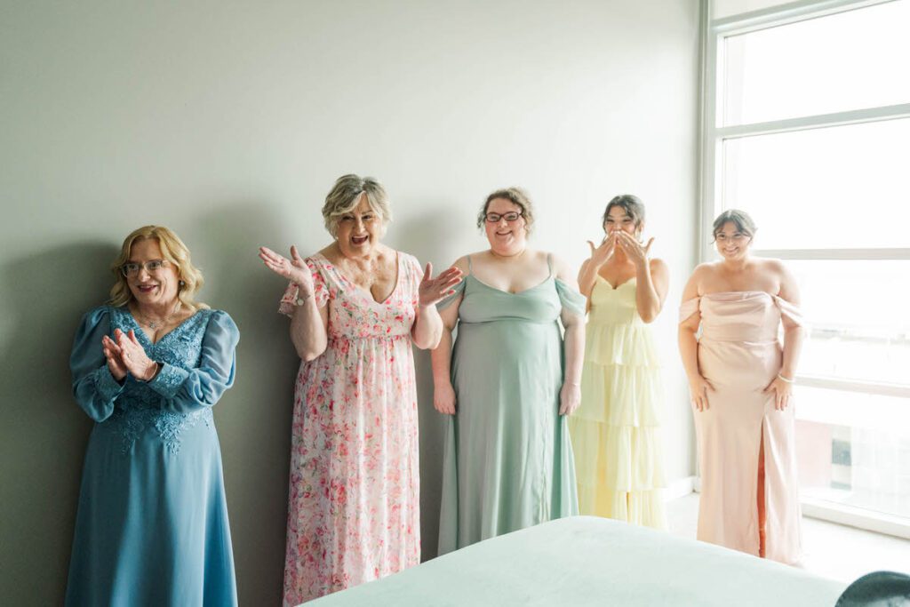 Bride revealing her dress to her bridesmaids and family