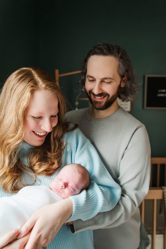 A new mom and dad smile while posing with their newborn baby.
Louisville In Home Newborn Session
Photos by Michelle Bordenkircher Photography