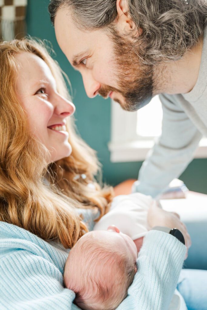 A new mom and dad smile at each other while posing with their newborn baby.
Louisville In Home Newborn Session
Photos by Michelle Bordenkircher Photography