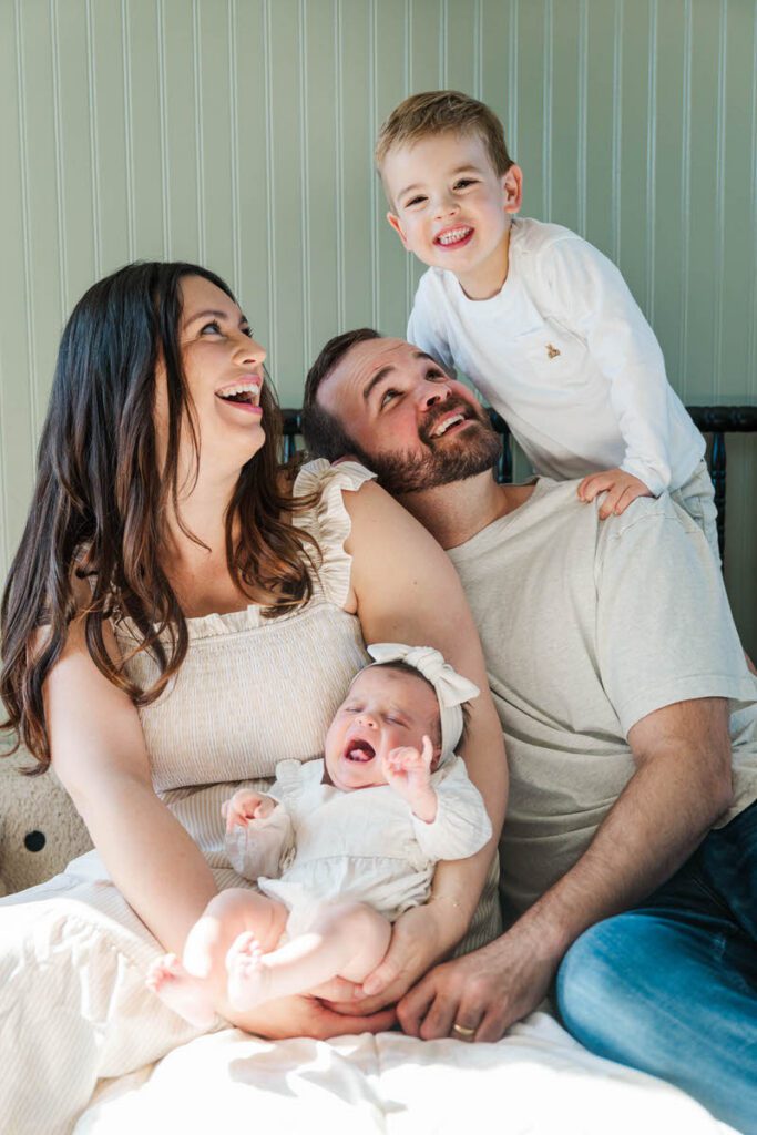 A mom and dad smiling at their new baby during their Louisville In-Home newborn session Photos by Michelle Bordenkircher Photography