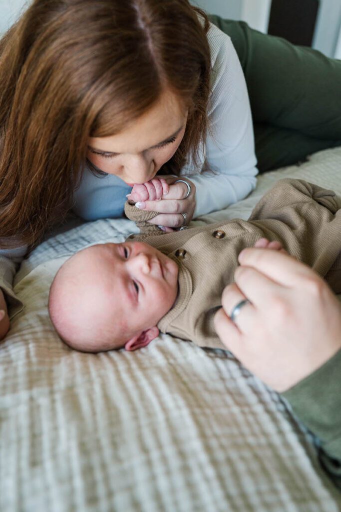 A mom gives her son's hand a sweet kiss during his Louisville In-Home newborn session
Photos by Michelle Bordenkircher Photography
