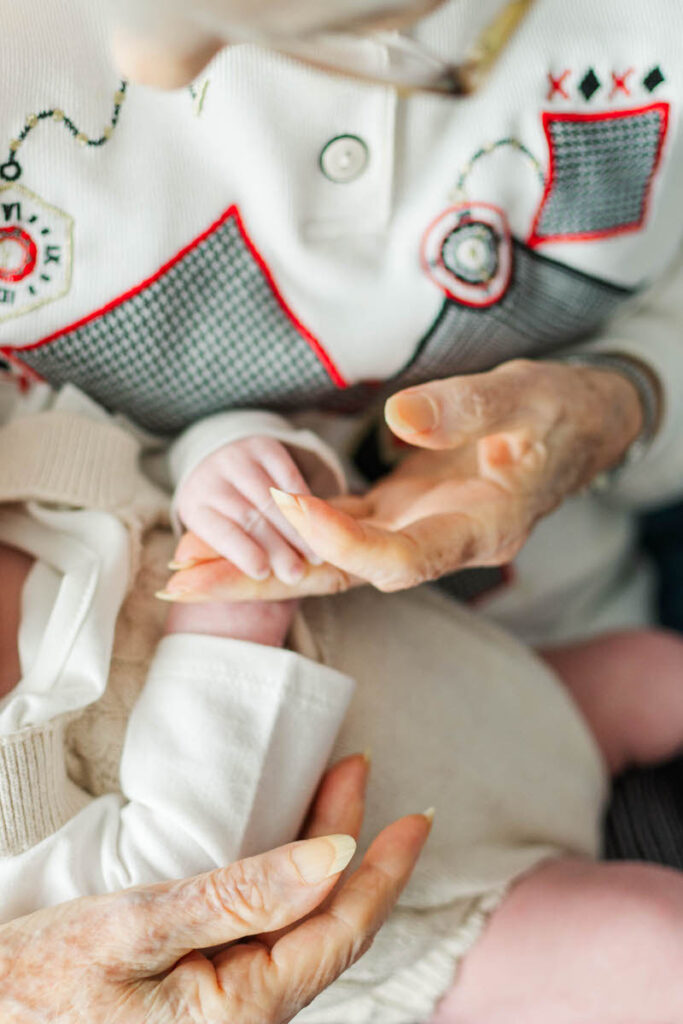 A Louisville great-grandmother holds a newborn baby's hand during extended family photos.