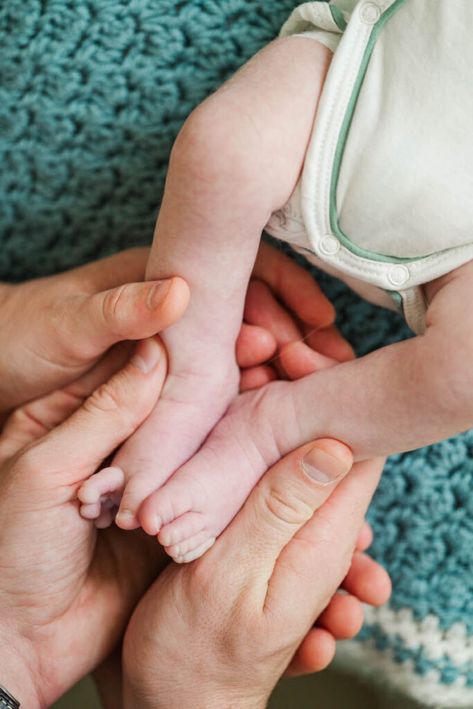 Mom and dad hold newborn baby's toes during their baby's first year photography. 
