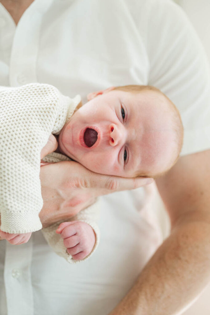 baby yawns while dad holds him during Louisville newborn session