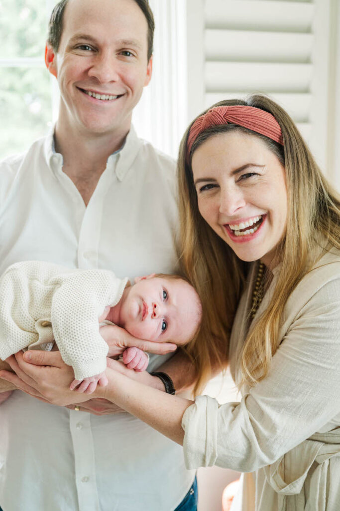 A Louisville mom and dad smile with baby during their in-home newborn session