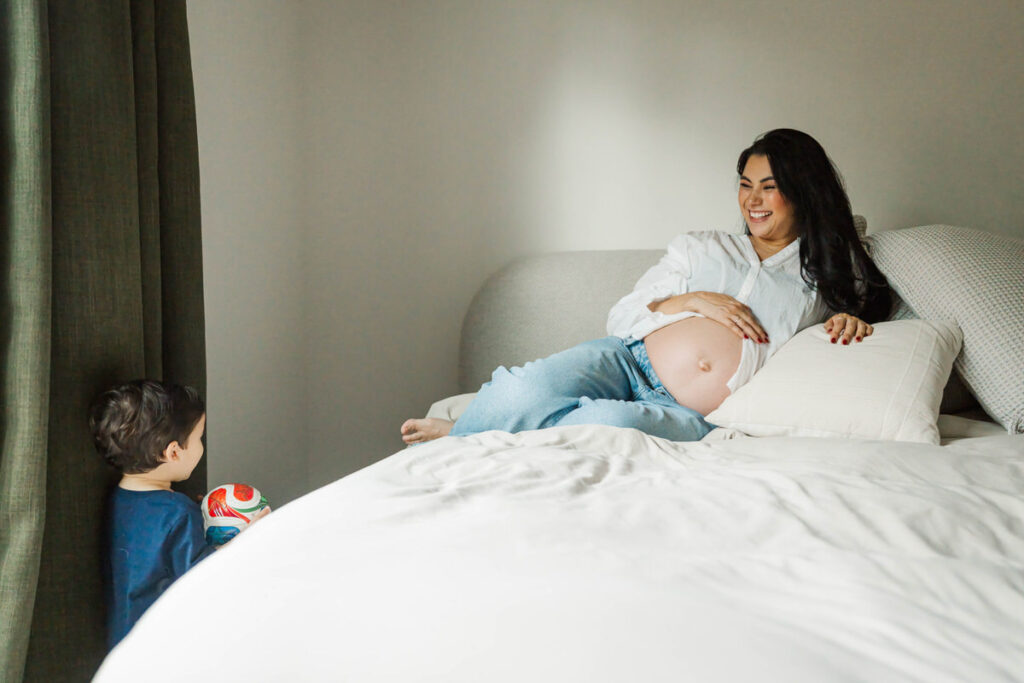 Mom smiles at son while taking her in-home maternity photos.