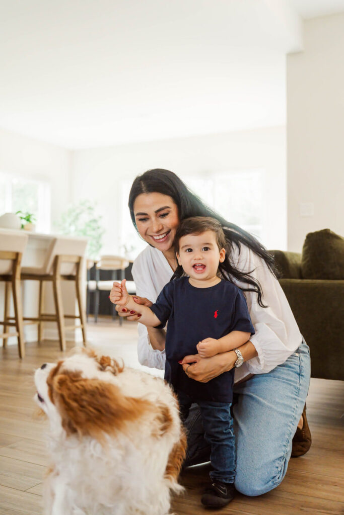 Mom and son laugh while feeding their dog during their in-home maternity session.