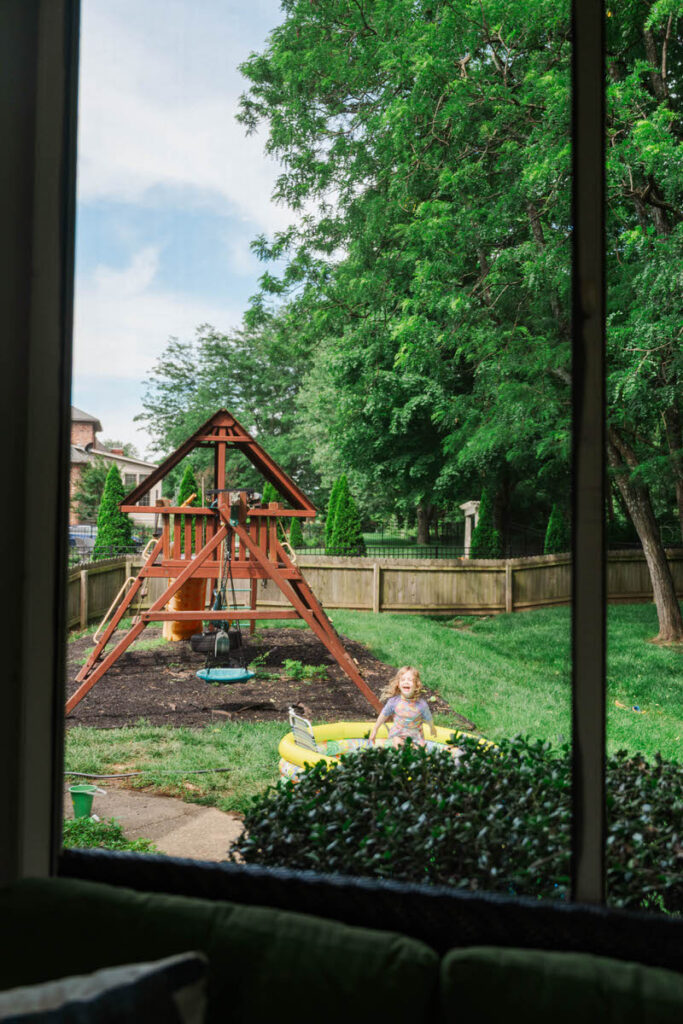 Louisville girl splashes in kiddie pool in her backyard for her summer in-home family session.