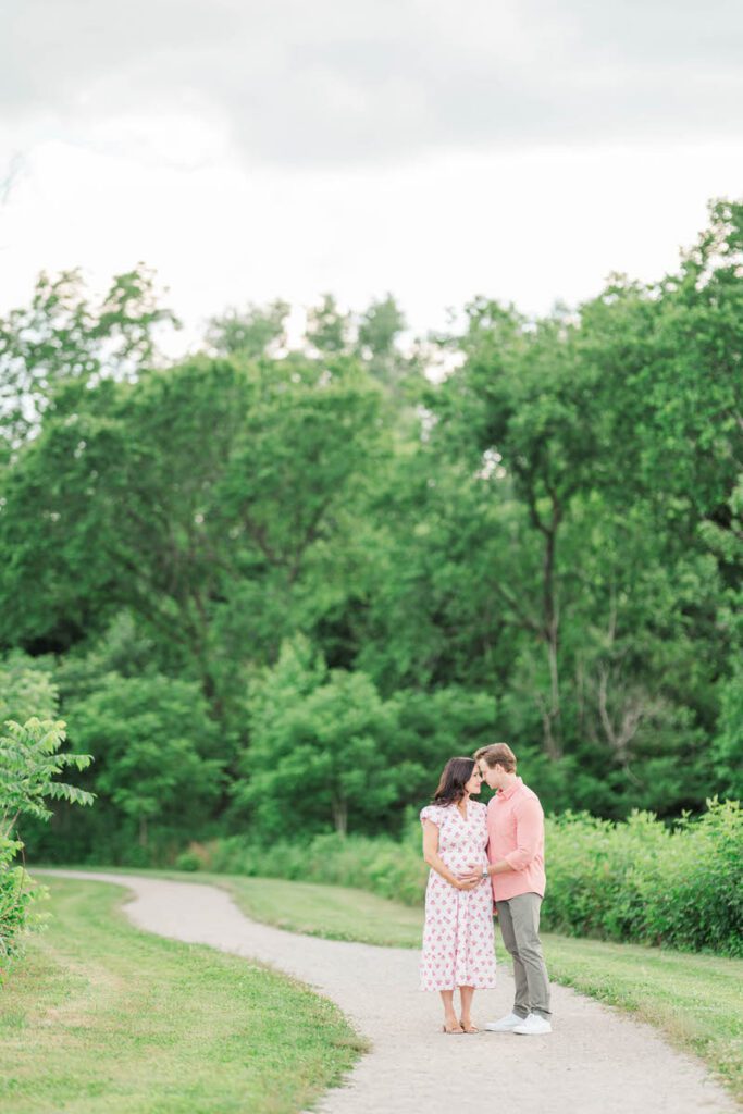Expecting parents smile at each other in Beckley Creek Park