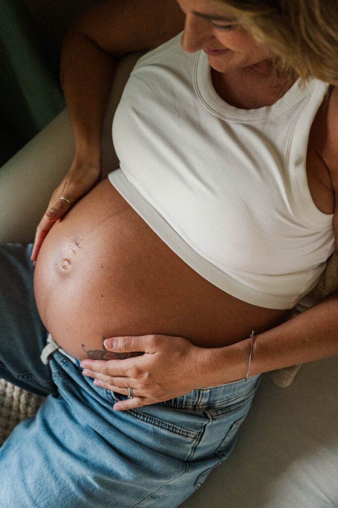 An expecting mama hugs her belly during her in-home session