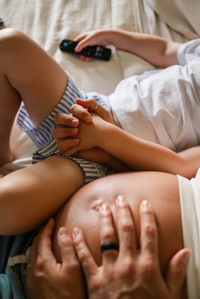 An expecting mama holds her son's hand, in an example of what to wear during an in-home maternity session