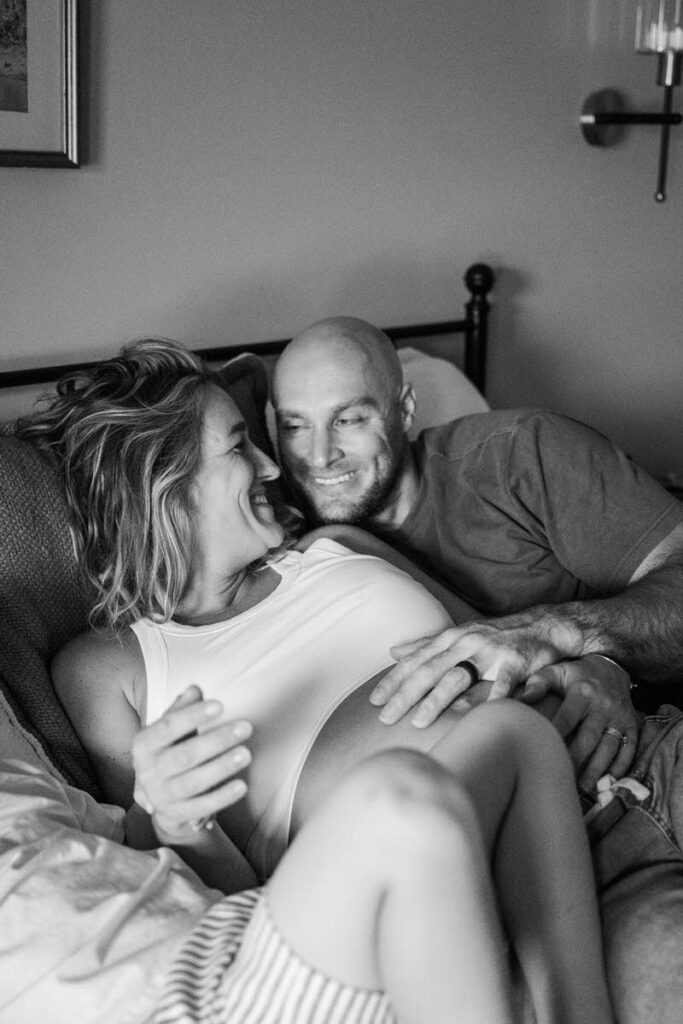 Expecting parents smile at each other during their in-home maternity session in Louisville, KY