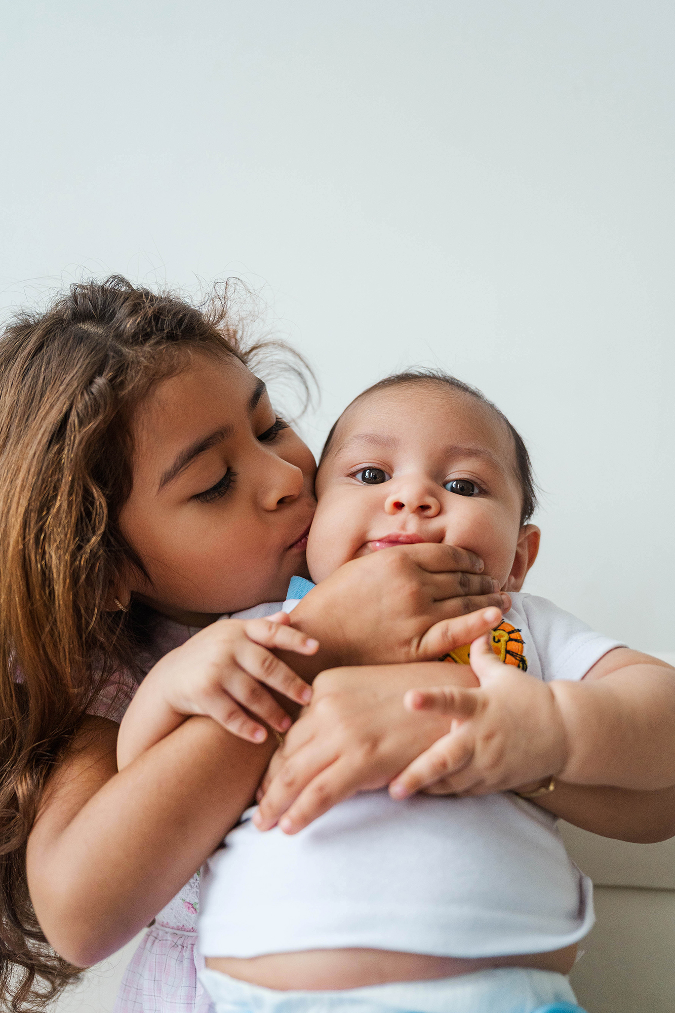 Big sister kisses her baby brother's cheek during a Louisville Portrait Photographer family session
