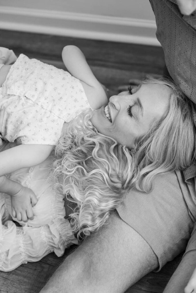 Toddler girl gives her mom a hug on the floor.