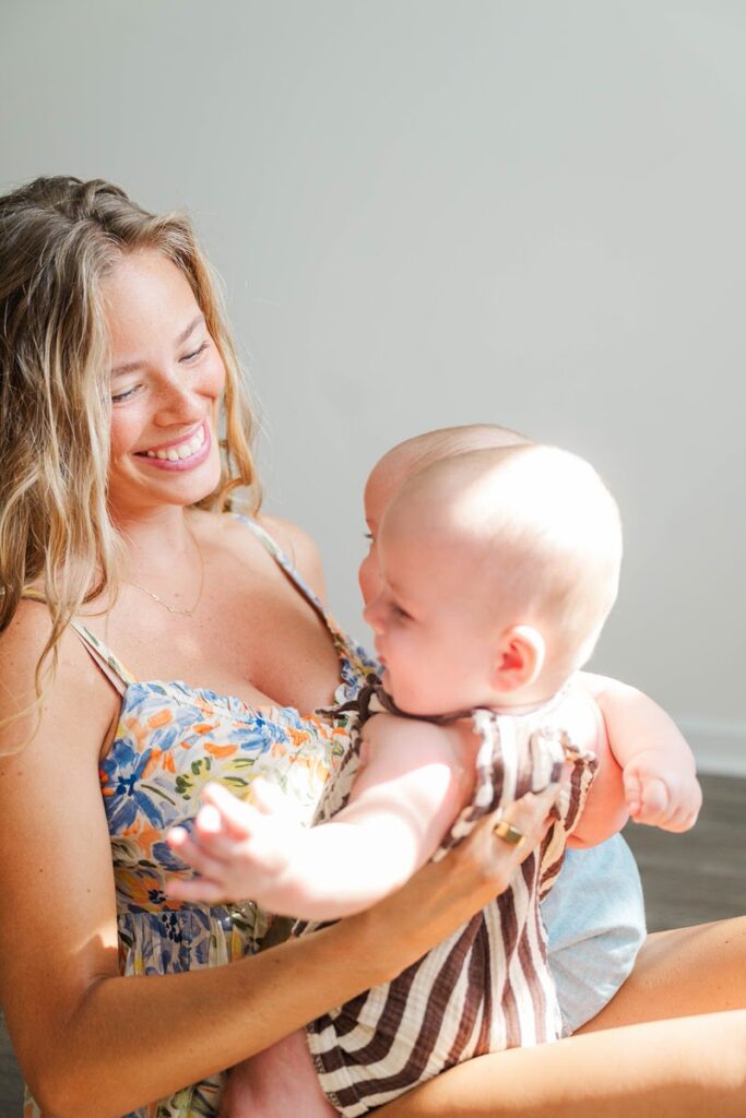 Mom smiles at twin seven month old boys during their in-home family session.