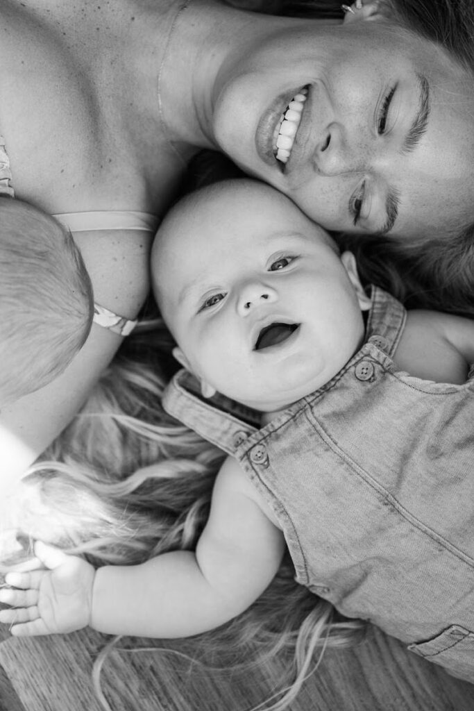 Mom and sons lay on floor together and play during their in-home family photos.