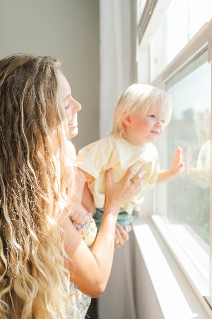 Mom and toddler look out the window during their in-home photos.