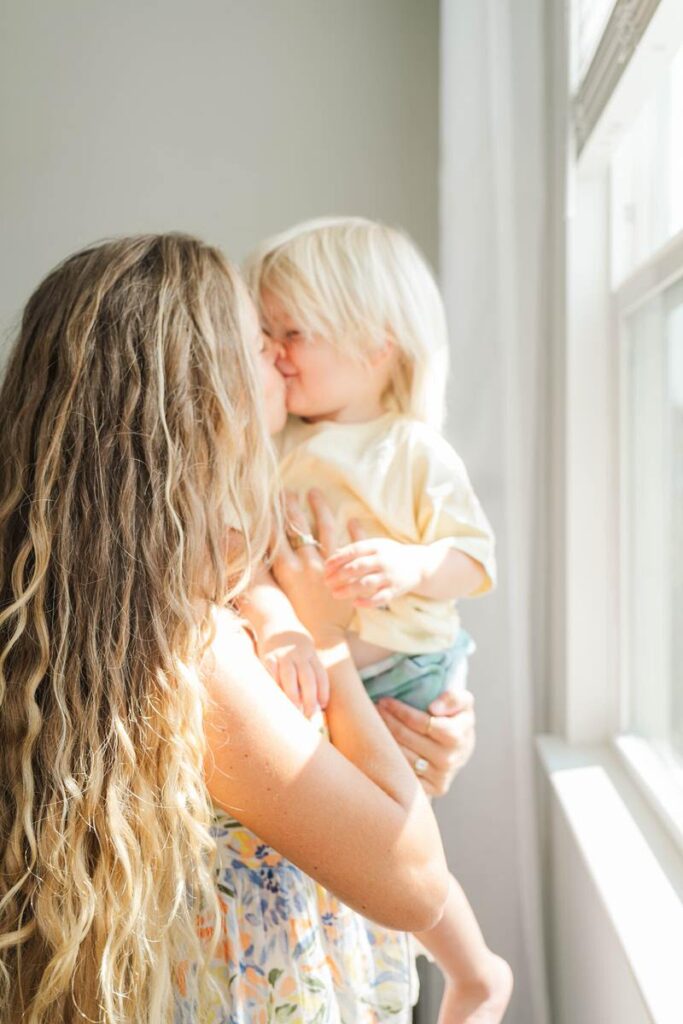 Mom gives her toddler son a kiss during their in-home photo session.