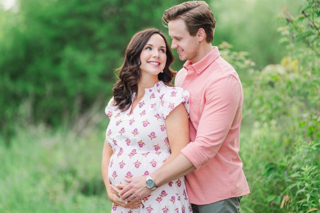 Expecting parents smile at each other during their Louisville maternity session.