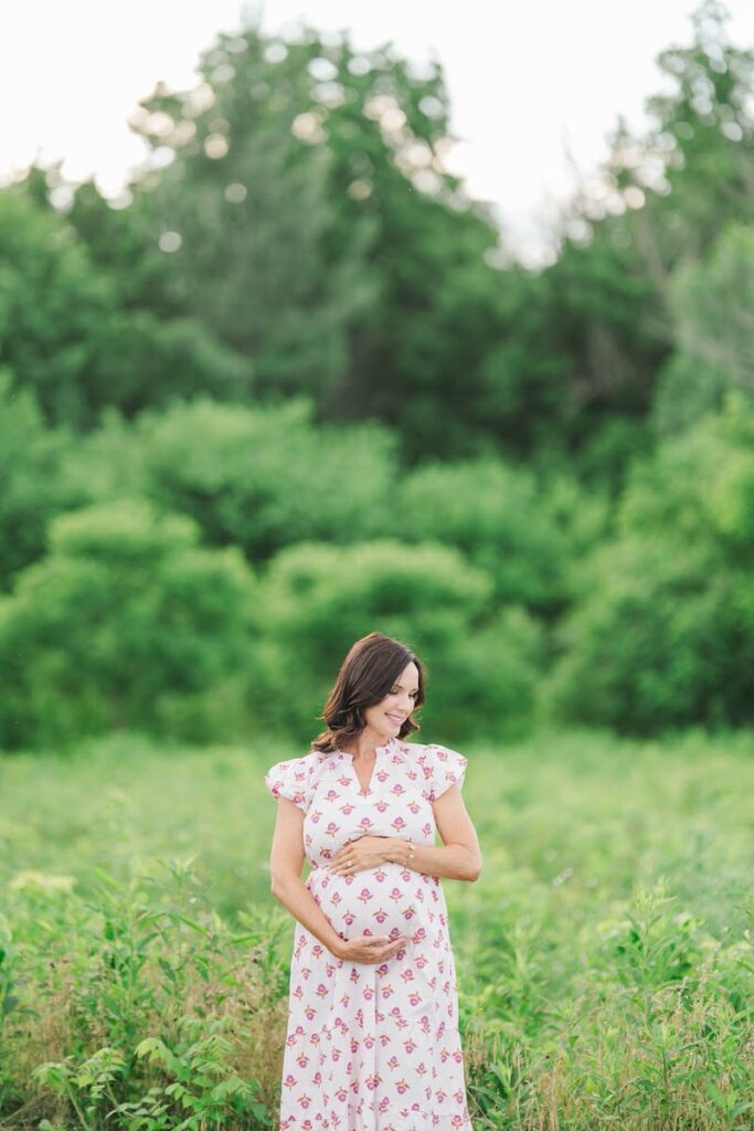 Expecting mom smiles and holds her baby bump during her Louisville maternity session.
