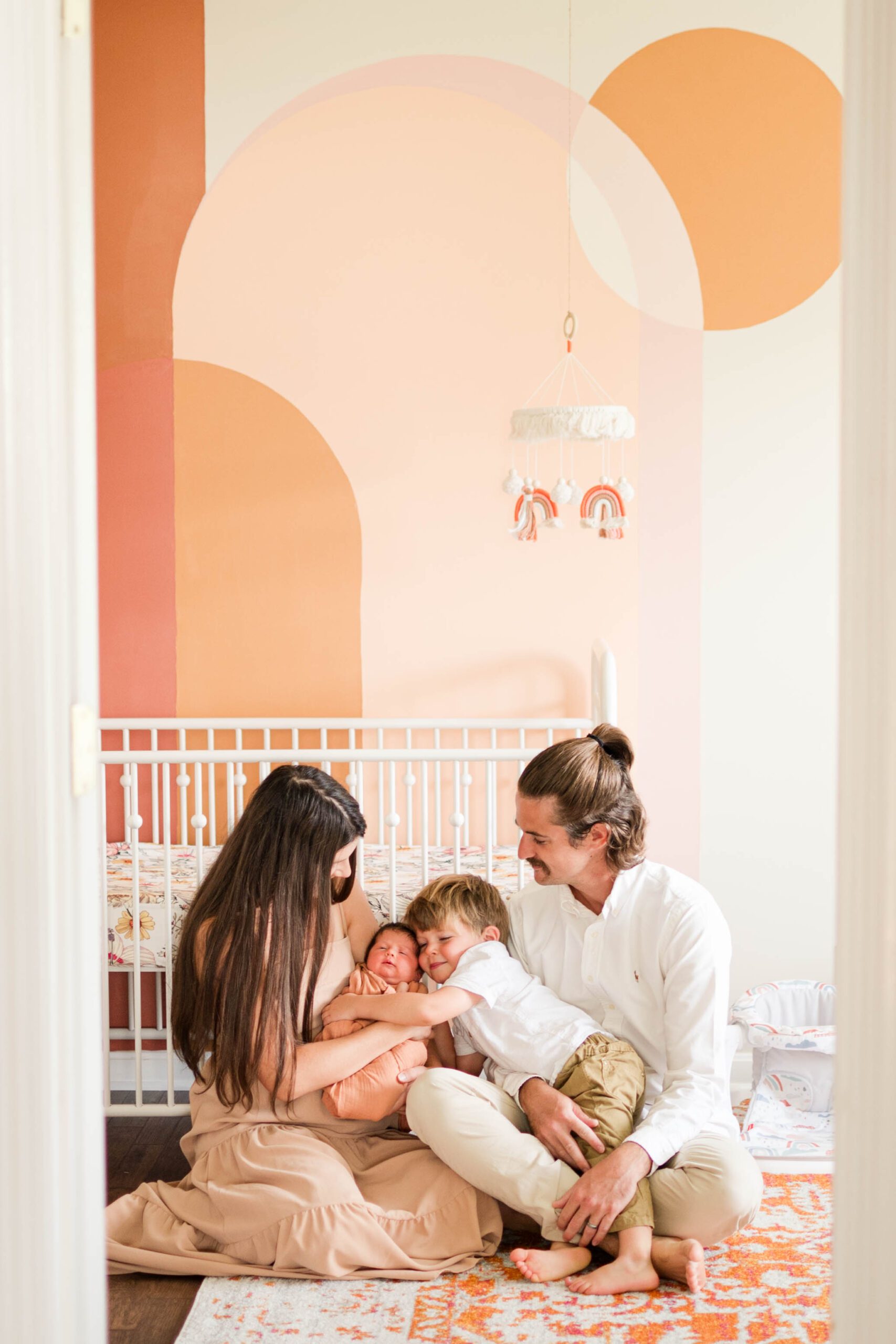 Family holds newborn baby in front of crib in nursery