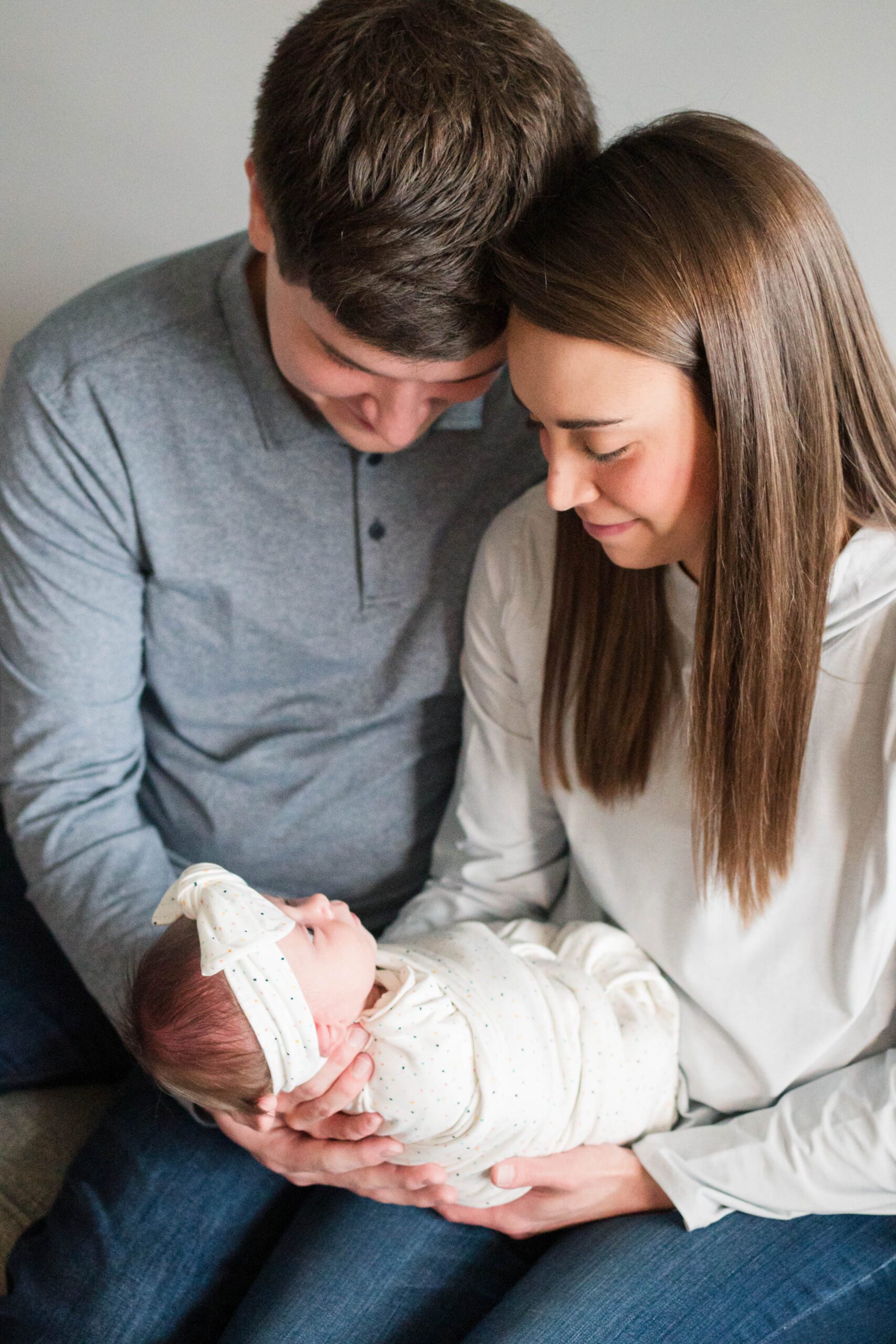 Mom and dad hold newborn baby in their home