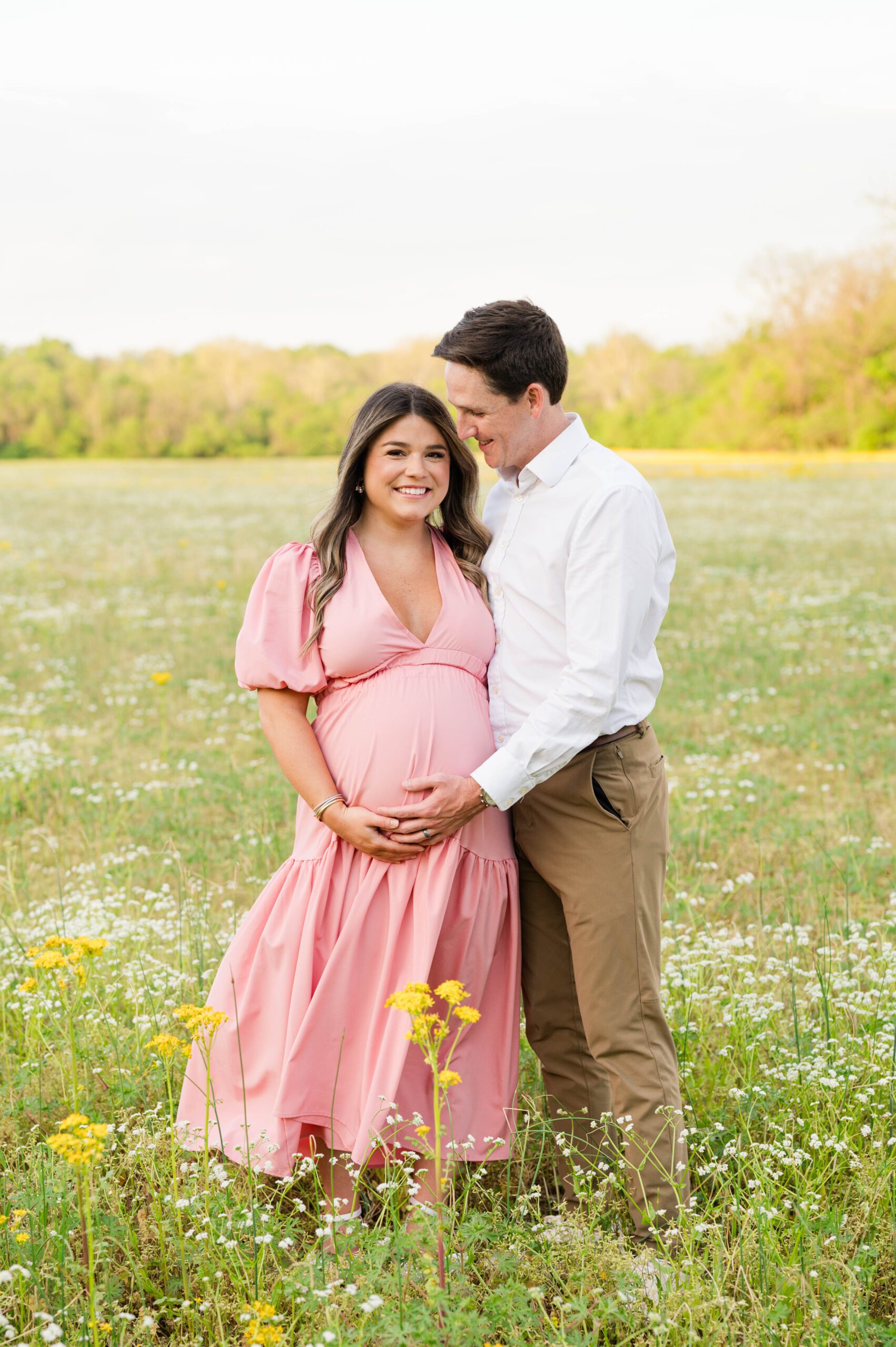 Couple embraces in a field of wildflowers for their maternity session