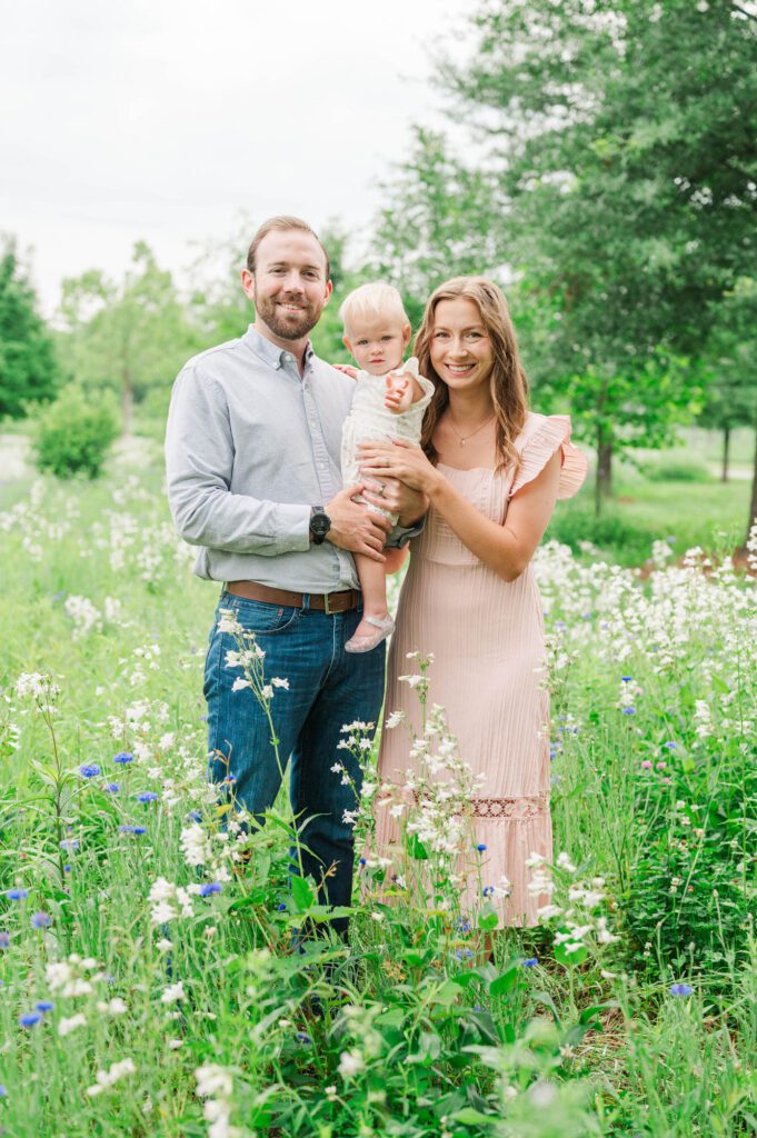 Mom and dad hold their baby in the wildflowers at Beckley Creek Park