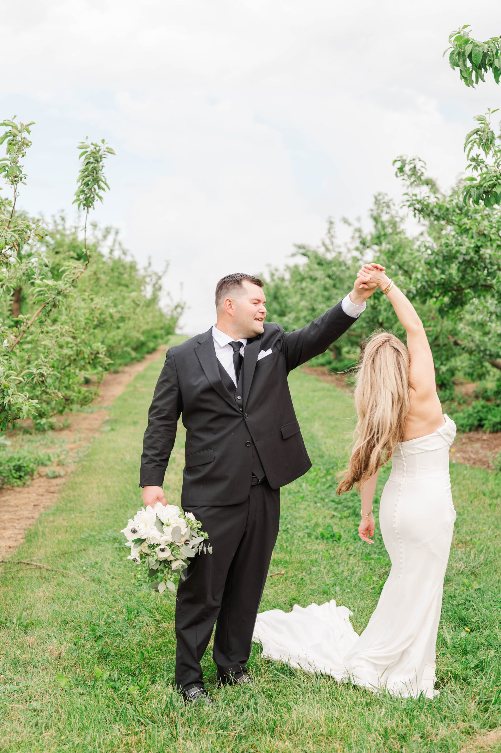 Couple dances in orchard immediately following their wedding ceremony